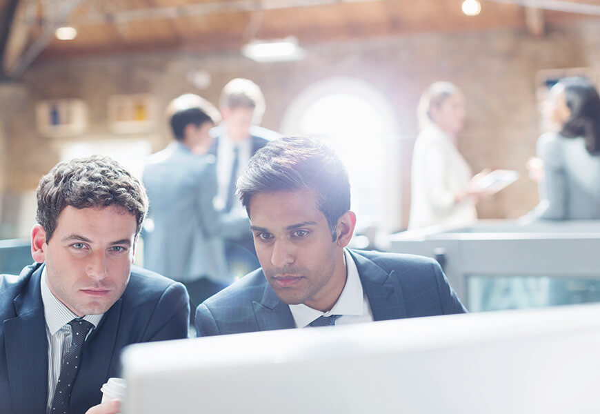 Two men in an office look intently at a screen Two men in an office look intently at a screen